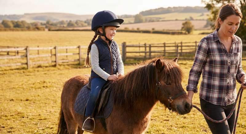 Kind mit Reithelm auf Pferd